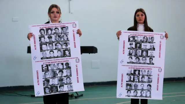Dua orang pelajar perempuan menunjukkan plakat berisi foto para korban mafia di Italia. 