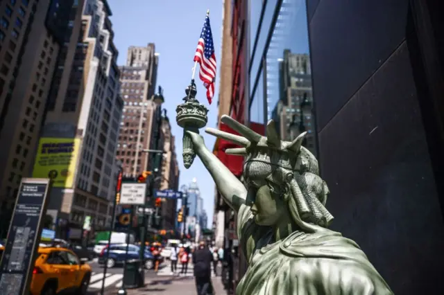 АҚШ давлат байроғини кўтариб турган Озодлик ҳайкали ўрнатилган кўчанинг акси.