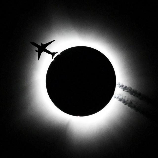 Un avión pasa cerca del eclipse solar total durante la Hoosier Cosmic Celebration en el Memorial Stadium de Bloomington, Indiana, EE.UU.