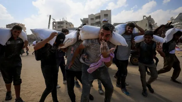 Палестиналыктар гуманитардык жардам таратуучу жайдан бир каптан ун алып кетип баратышат