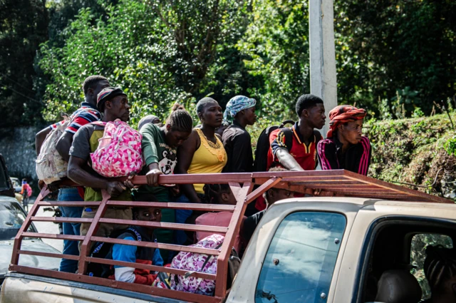 Gente carga mochilas y bolsas con sus pertenencias mientras huyen, en la parte de atrás de una pick up, de la violencia en el distrito Kenskof de Puerto Príncipe, Haití, el 29 de enero de 2025. 