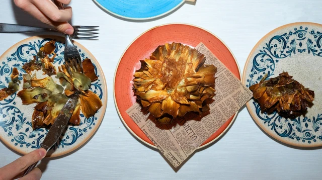 접시 위에 음식이 놓여 있고, 한 사람이 포크와 나이프를 사용하고 있다.