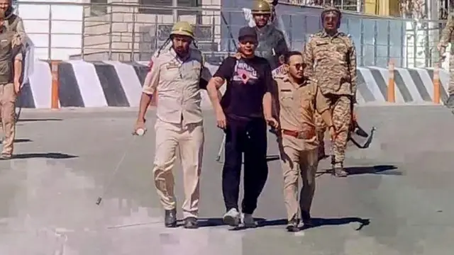 हिंसा के दौरान एक प्रदर्शनकारी को गिरफ़्तार कर ले जाती पुलिस