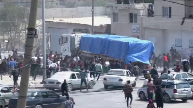 أشخاص يلاحقون قافلة من شاحنات المساعدات المتجهة إلى غزة