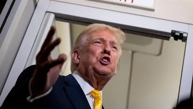 Donald Trump con traje oscuro y corbata amarilla.