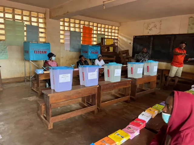 Un bureau de vote avec des urnes déposées sur des tables et des bulletins de vote.
