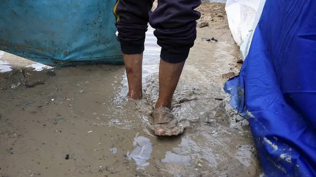 Los pies de un hombre caminando con el agua sucia hasta los tobillos