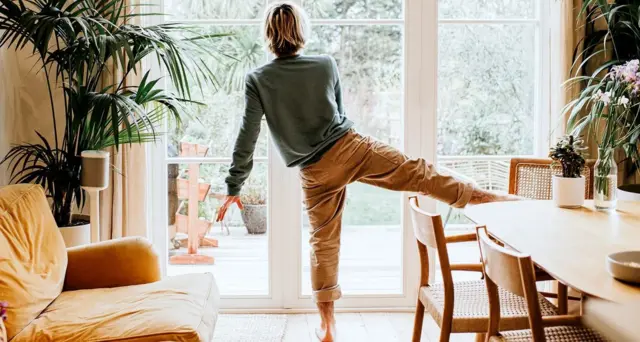Un homme effectuant un exercice d'équilibre dans un salon ou une salle à manger. 