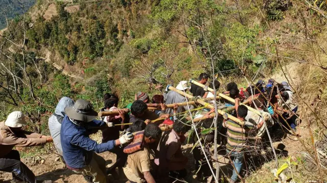 खानी क्षेत्रमा अनुसन्धानका लागि ड्रिल गर्ने उपकरण बोकेर लैजाँदै कामदारहरू