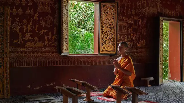 Monge ajoelhado no interior de um templo