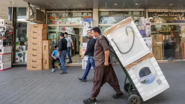 یک ایرانی در بازار امین حضور تهران در تاریخ ۳ اکتبر ۲۰۲۱ لوازم خانگی را جابجا می‌کند. 