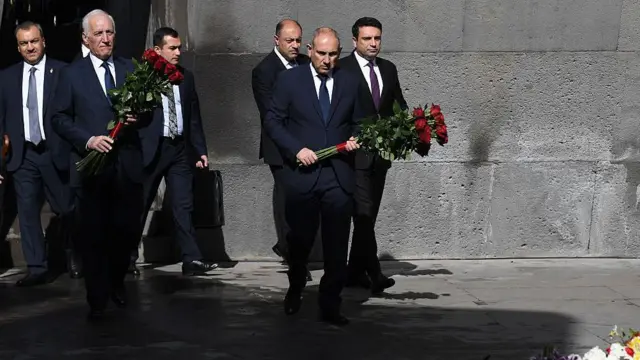 Paşinyan, 24 Nisan'da anma törenlerinin kalbi Tsitsernakaberd olarak bilinen "Ermeni Soykırımı Anma Kompleksi"ne çiçek bırakıyor. Yanında başka takım elbiseli yöneticiler var.