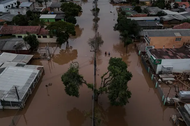 Imagem de drone mostra pessoas caminhando em uma rua inundada em Eldorado do Sul, no Rio Grande do Sul, em 10 de maio de 2024.