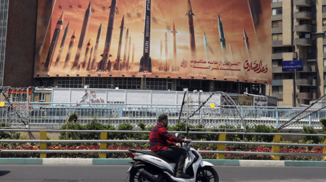 Motociclista passa por um outdoor anti-Israel com fotos de mísseis iranianos em Teerã, Irã, no domingo (15/4)