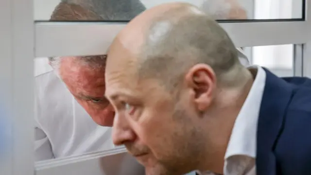 двое мужчин переговариваются по разные стороны решетки