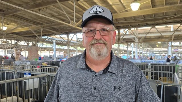 一位留着胡须、戴着帽子的男子站在州博览会