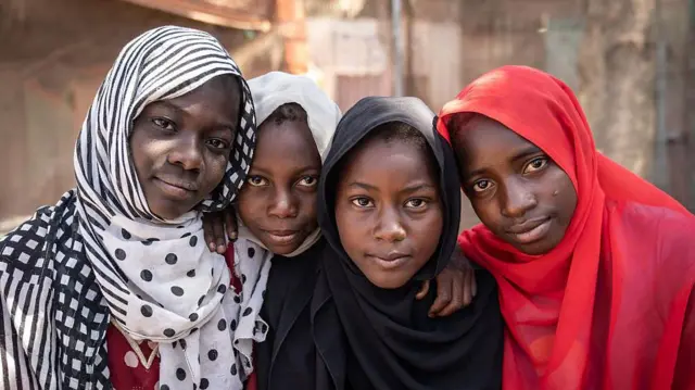 ثلاث فتيات نازحات في مركز رعاية صحية أولية متنقل مدعوم من برنامج الأمم المتحدة الإنمائي في موقع تجمع للنازحين في كسلا