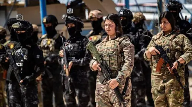 Suriyeli Kürt savaşçılar ellerinde silahlarla yan yana duruyor - 18 Nisan 2025