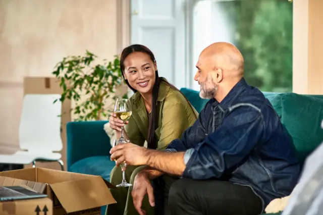 Una pareja joven y exitosa con unas copas de vino en la mano brindando