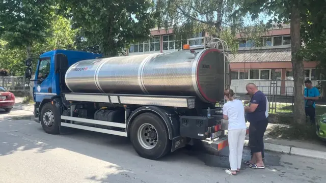 Мушкарац и жена точе воду из цистерне