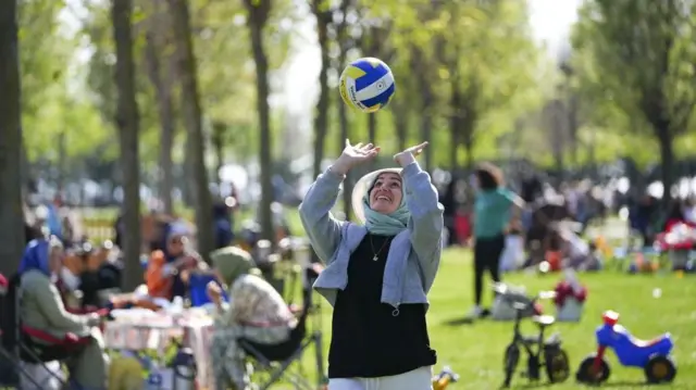 Une femme jouant avec un ballon dans un parc public.