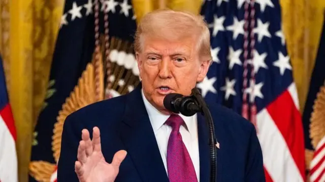 Donald Trump ABD bayrağı önünde konuşma yapıyor 