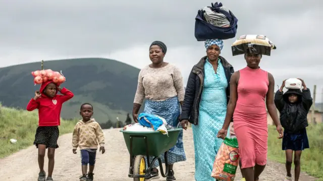 A family returns home along a dirt track in the Eastern Cape in South Africa after receiving food parcels from a non-governmental organisation