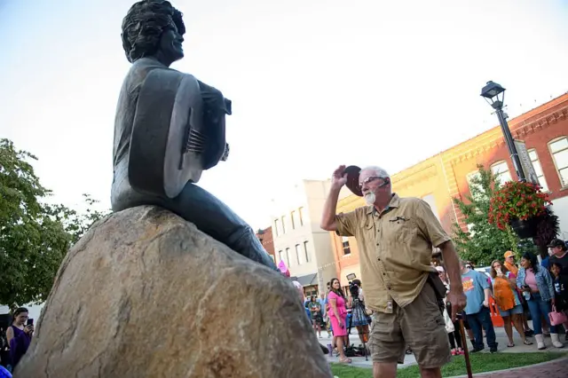 Un hombre se quita el sombrero ante la estatua de Dolly Parton en Tennessee.