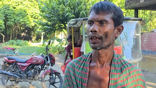 হালিম উদ্দিন আকন্দের বড় ছেলে গায়ে একটি সবুজ গামছা জড়িয়ে দাড়িয়ে আছে