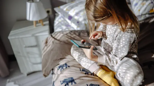 Bir kız çocuğu elinde telefon ekrana bakıyor