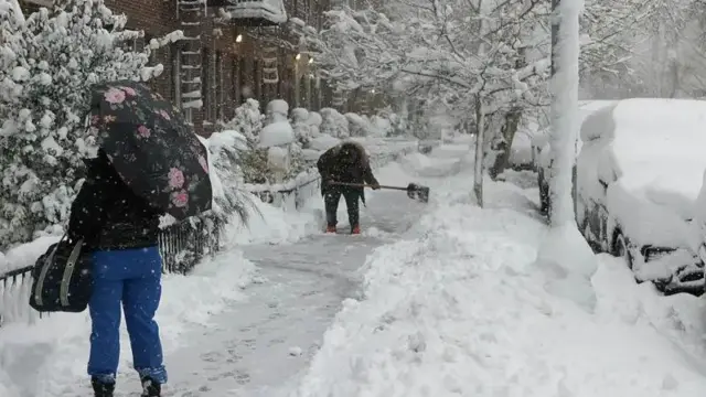 Pesin dey shovel snow during one winter storm for di Brooklyn borough of New York