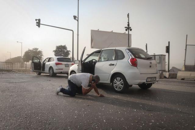 سائق يخرج من سيارته ويجري مكالمة هاتفية من الأرض، في أعقاب انفجار مرفأ بيروت الضخم، في بيروت، لبنان، يوم الثلاثاء 4 أغسطس/آب 2020. 