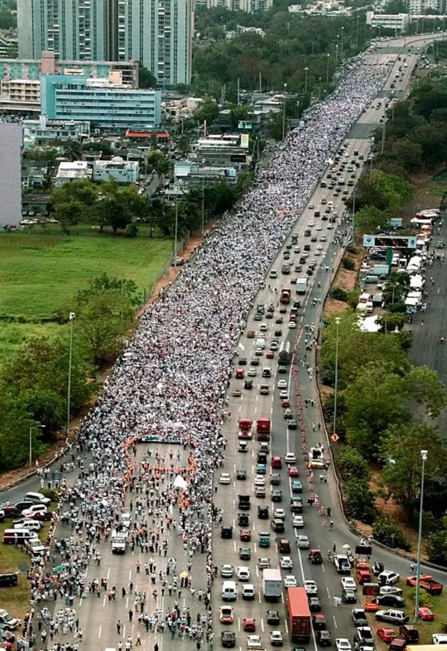 Una larga avenida en Puerto Rico luce desbordada por miles de personas que marchan.