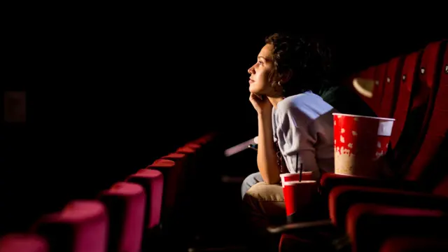 Una mujer ve una película en el cine.