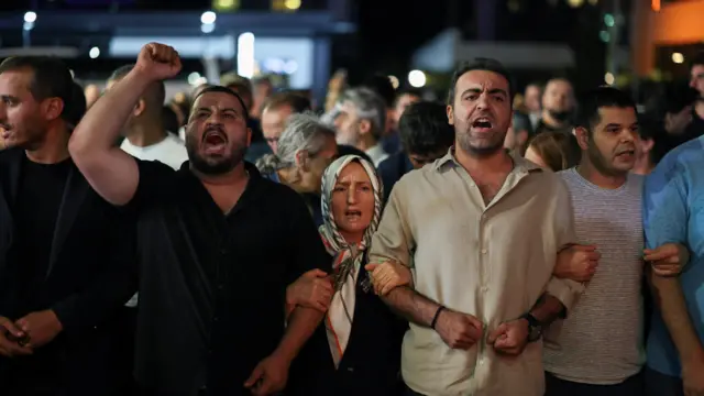 kol kola girmiş insanlar, bir erkeğin yumruğu havada 