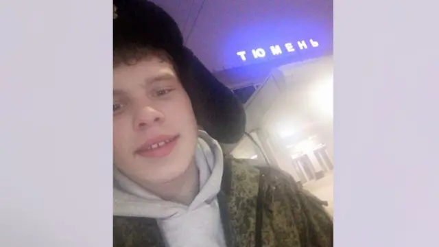 A young man wearing a Russian hat and a khaki top