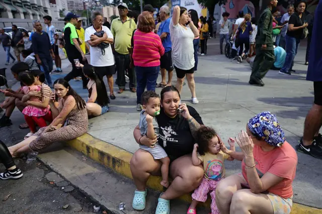Personas evacuadas hablan por teléfono mientras aguardan en el complejo urbanístico Parque Central, en Caracas, tras el terremoto de magnitud 7,2 que sacudió Venezuela