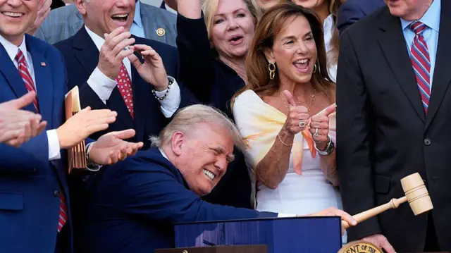 Donald Trump hitting di gavel, oda politicians dey im back dey smile and cheer am