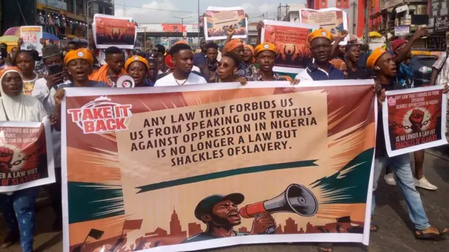 Pipo wey wear orange beret holding a banner