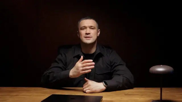 кадр из видеообращения Федорова: мужчина в темной одежде на черном фоне сидит за столом и жестикулирует