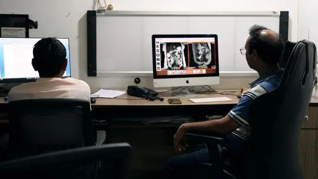 Dr KK Gupta, a radiologist in Meerut sits at a desk analysing MRI scans on a computer screen