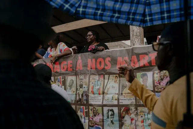 Un manifestant se tient à côté d'une pancarte sur laquelle figurent les noms et les photos des victimes, lors d'une manifestation réclamant justice pour au moins 65 personnes tuées lors des troubles politiques sous l'ancien président Macky Sall, malgré une loi d'amnistie de 2024, à Dakar, le 30 août 2025