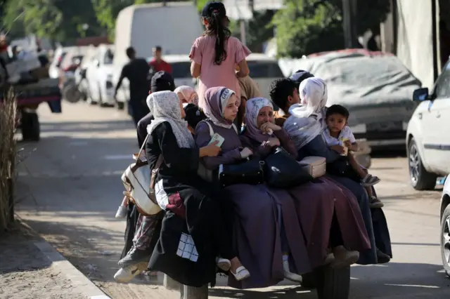 نساء وأطفال فلسطينيون يجلسون في الجزء الخلفي من سيارة خلال نزوحهم من دير البلح في وسط قطاع غزة في 21 أغسطس/آب 2024