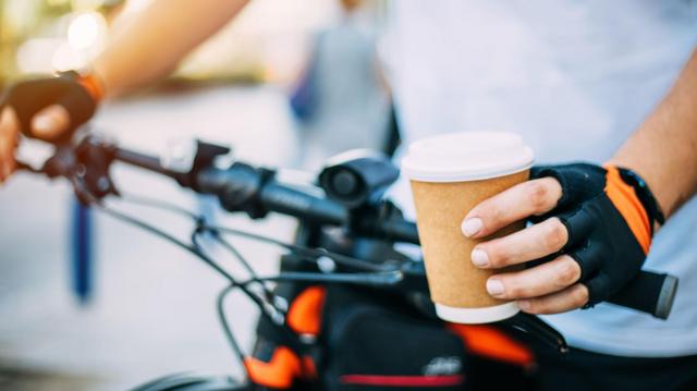 Mão de ciclista segurando copo de café