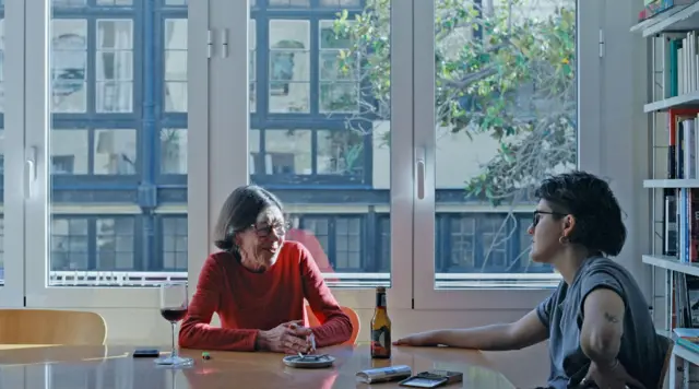 Marina Freixa (à direita) e a mãe, Mariona, sentadas à mesa, com um grande vão de janela ao fundo.