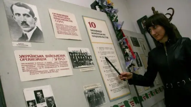 Дівчина показує на інформаційні матеріали на стіні музею Євгена Коновальця
