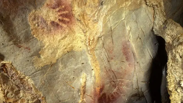 Fotografia de mãos marcadas em parede da caverna