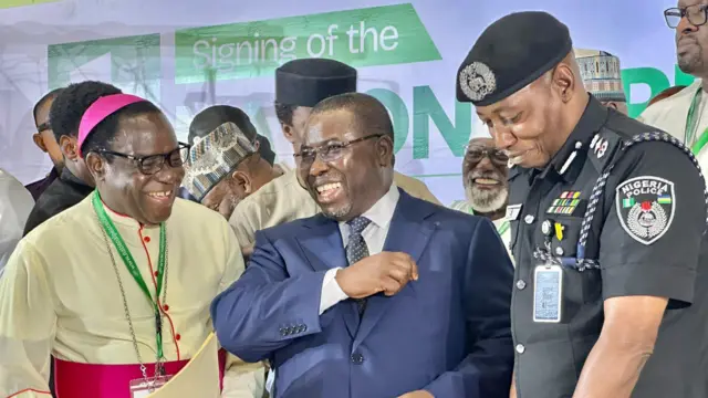 Nibi eto ikọwọbọwe alaafia naa, Alaga INEC ree laaarin, Ọjọgbọn Joash Amupitan. Alufaa ijọ ati ọlọpaa kan duro lapa osi ati ọtun rẹ