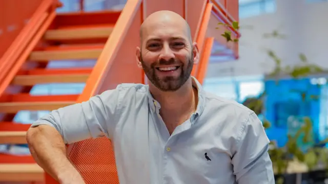 Homem sorrindo, apoiado em corrimão de escada