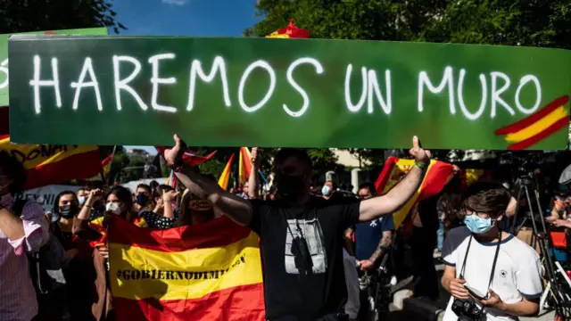 Simpatizantes do Vox, seguram placa que diz: Faremos um muro